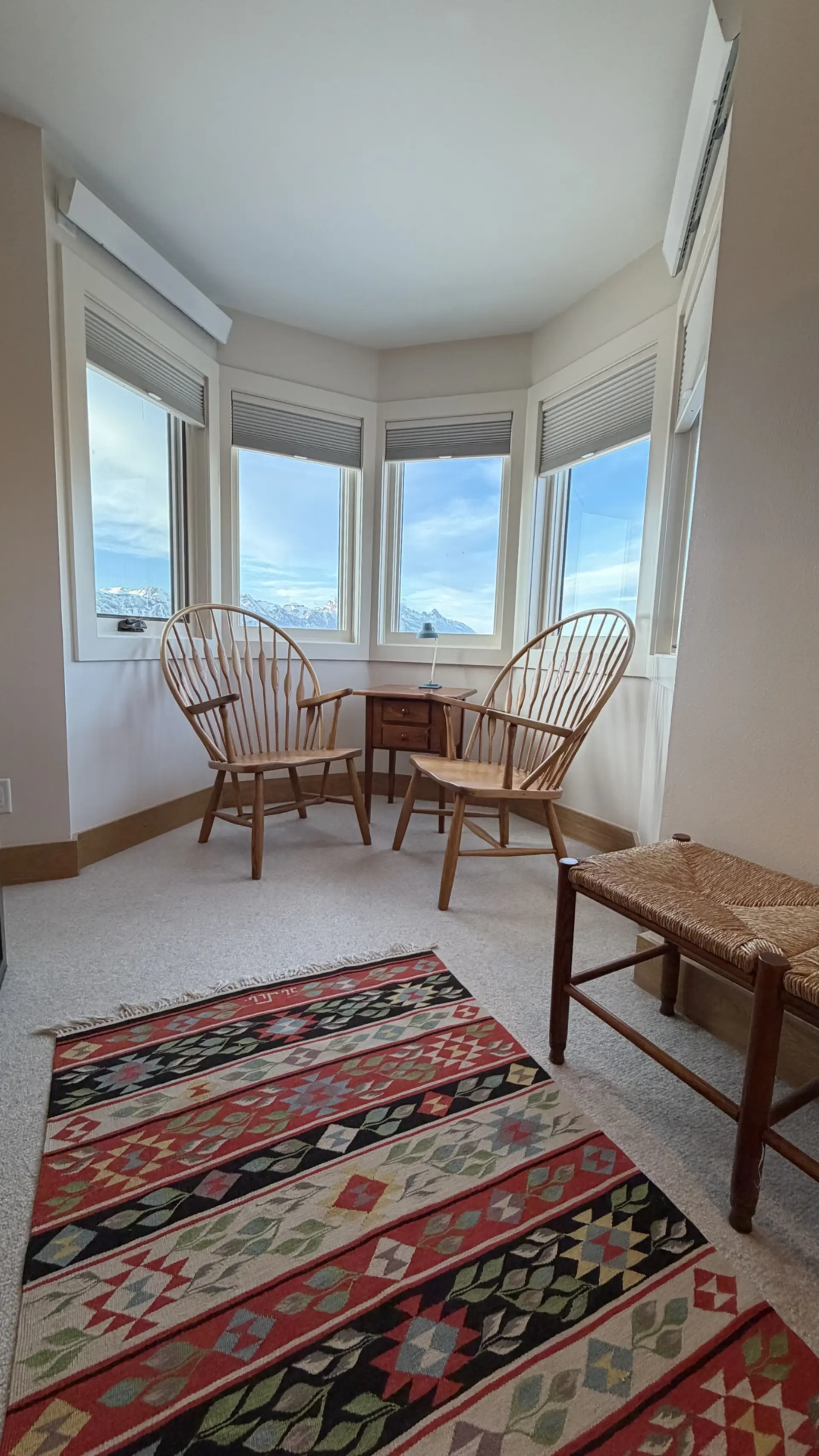 Luxury vacation rental living room at Spring Creek Ranch featuring river stone fireplace, leather seating, and panoramic Grand Teton mountain views