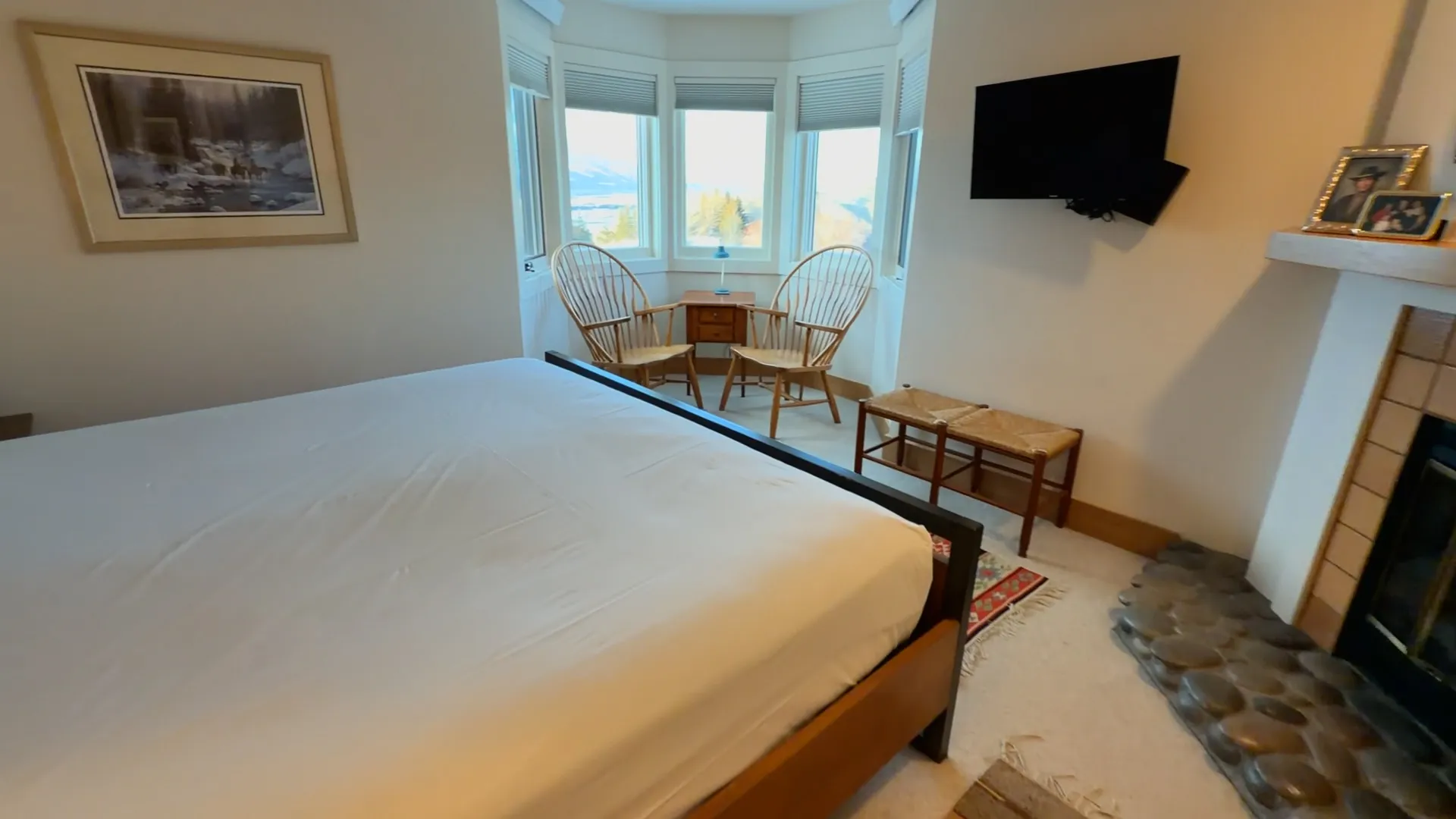 Master bedroom with king bed, bay window seating area, fireplace and wall-mounted TV - Spring Creek Ranch Jackson Hole