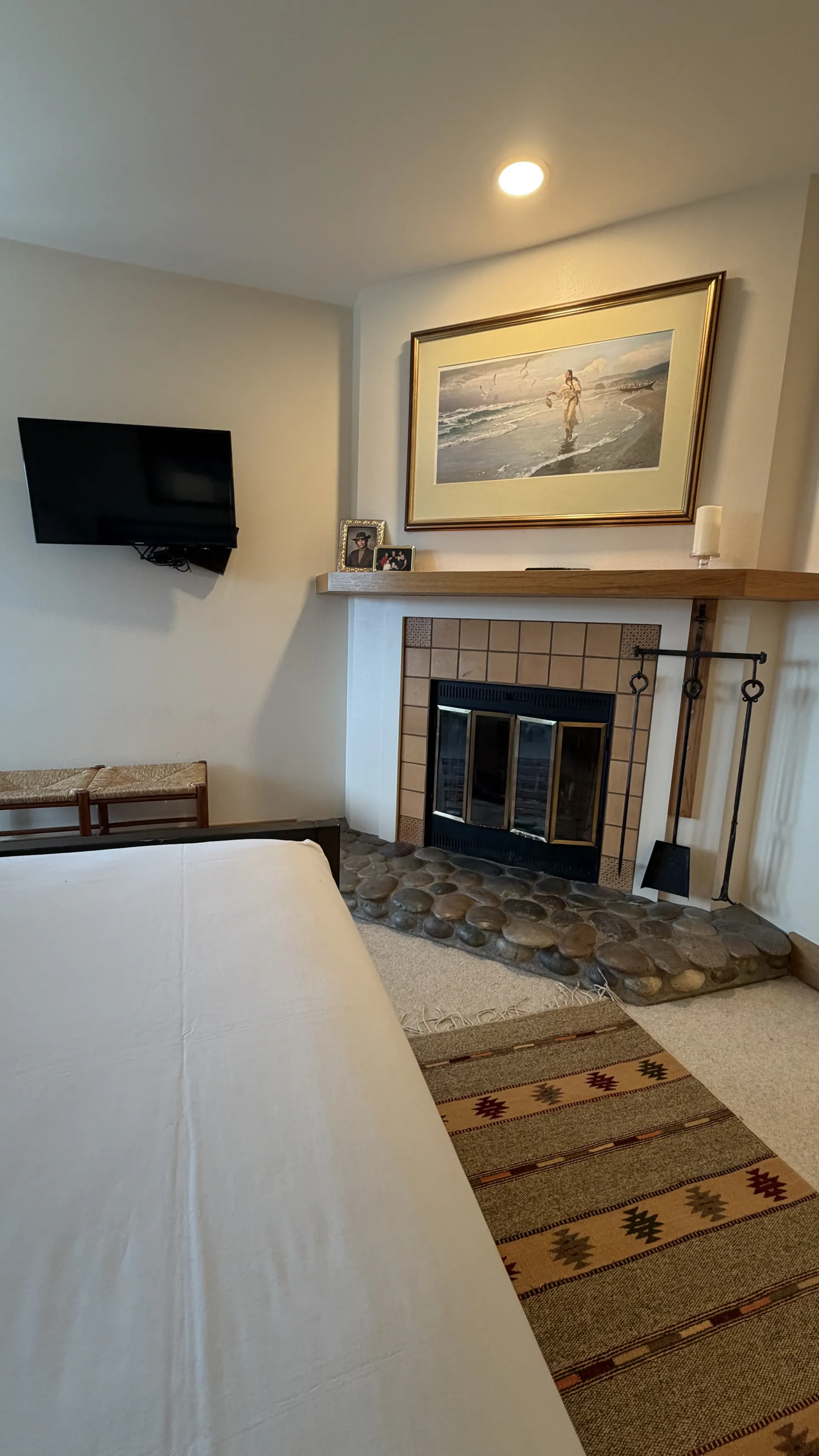 Master bedroom fireplace with river stone hearth, wall-mounted TV and artwork above mantle - Spring Creek Ranch Jackson Hole
